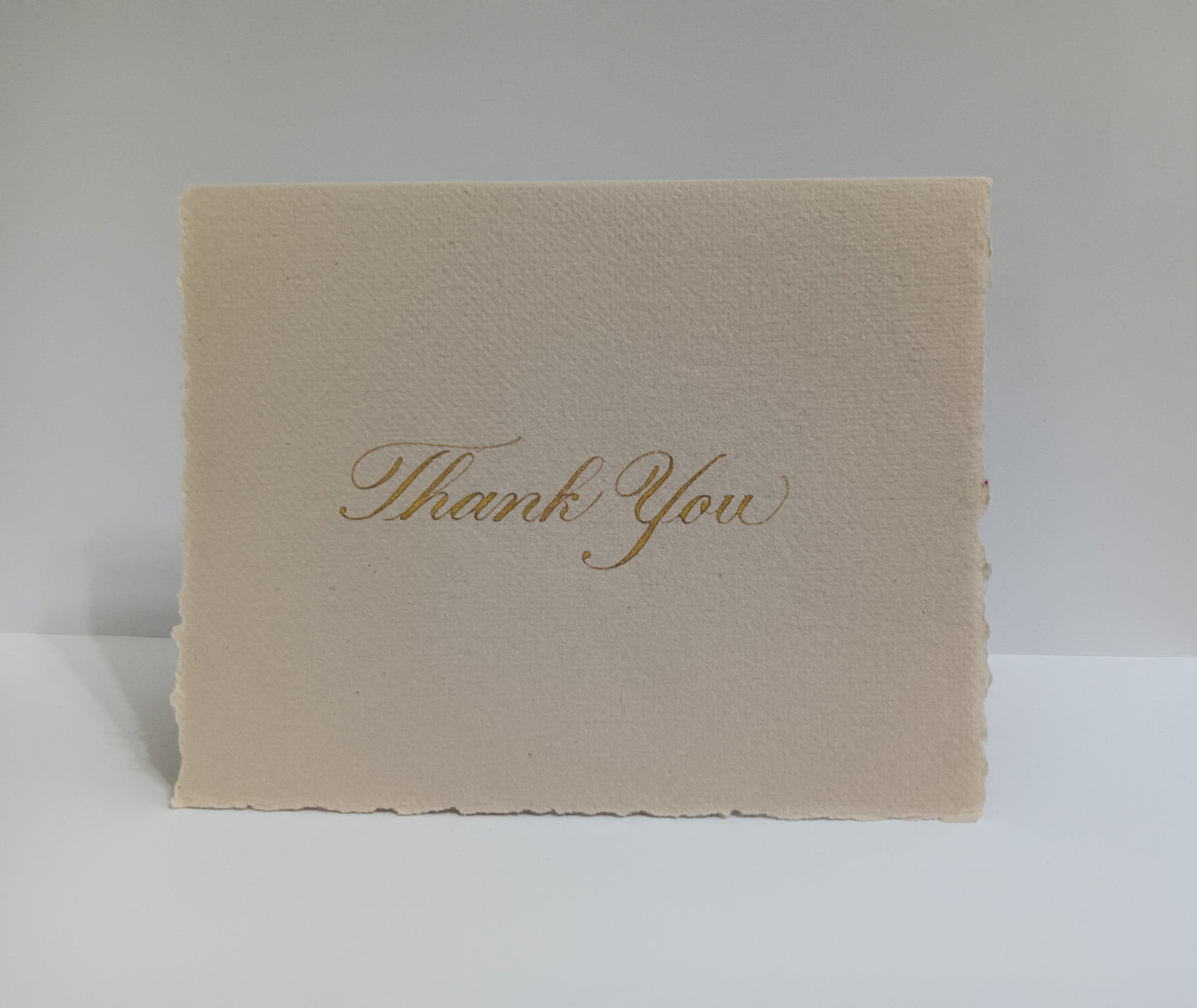 Beige card with 'Thank You' in gold on a white background