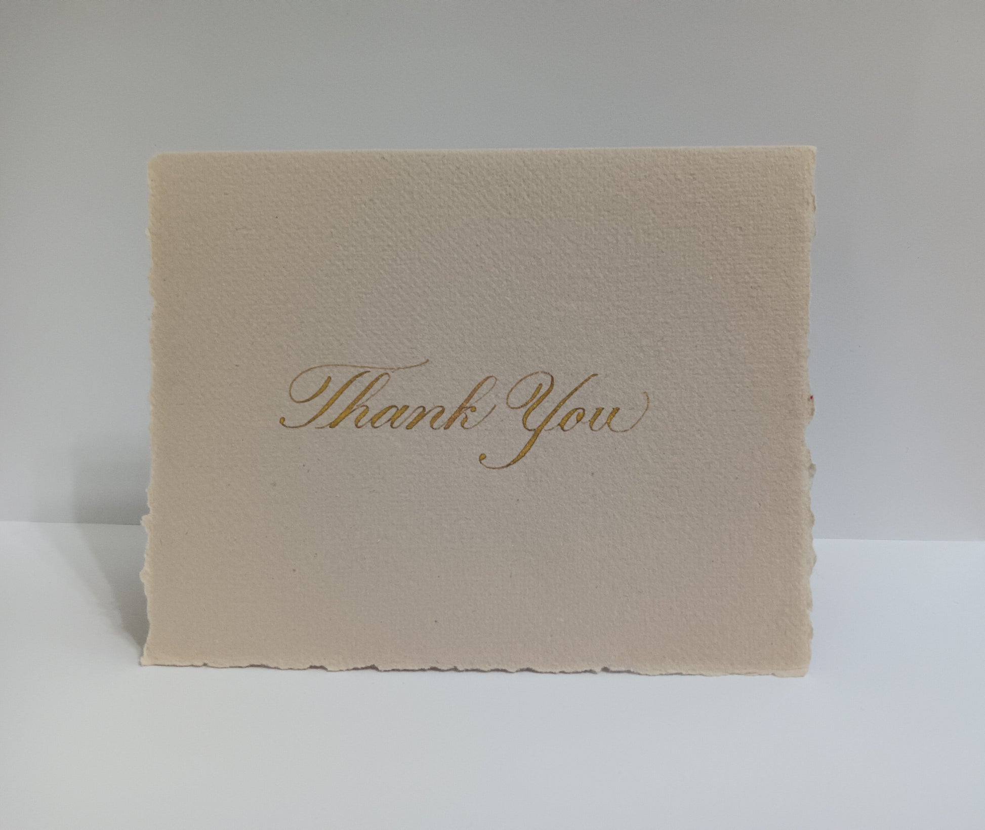 Beige card with 'Thank You' in gold on a white background